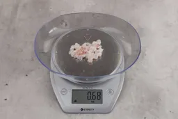 0.68 ounces of ground chicken scraps from garbage disposal, displayed on digital scale, placed on granite-looking table. Mess of soft tissue and pieces of shredded cartilage.
