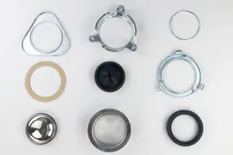 Parts of 3-Bolts Mount assembly on white platform, including backup flange, mounting ring, snap ring, fiber gasket, stopper, cushion mount, sink flange with “Disposall” engravings, removable sink baffle, lower mounting ring.