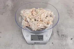 7 ounces of ground fish scraps from garbage disposal, displayed on digital scale, placed on granite-looking table. Few pin bones among a mess of raw fibrous tissue.