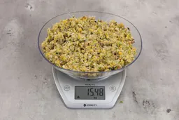 15.48 ounces of ground products from garbage disposal, displayed on digital scale, placed on granite-looking table. Mess of assorted scraps, including fibers, bones, etc.