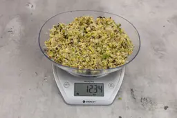 12.34 ounces of fish pin bones in mess of assorted scraps from garbage disposal on digital scale on granite-looking top.