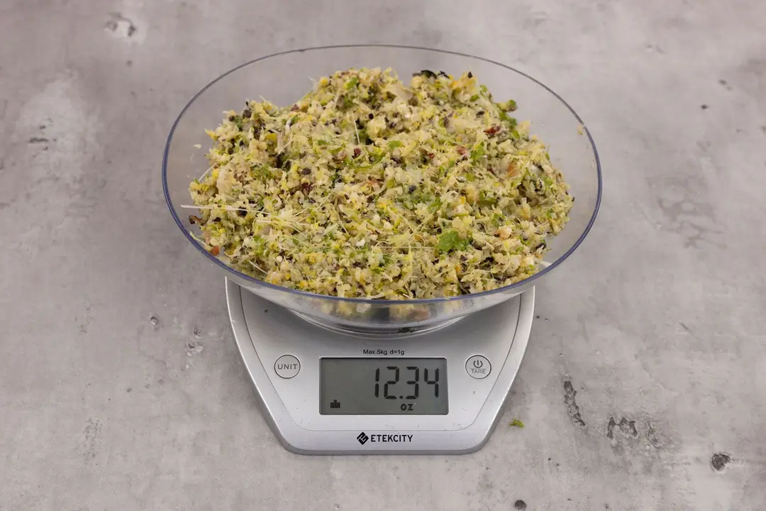 12.34 ounces of ground products from garbage disposal, displayed on digital scale, placed on granite-looking top. Visible fish pin bones in mess of assorted scraps, including dietary fiber, shredded bones, etc.