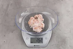 2.62 ounces of ground chicken scraps from garbage disposal, displayed on digital scale, placed on granite-looking table. Mess of fibrous soft tissue and shredded bones.