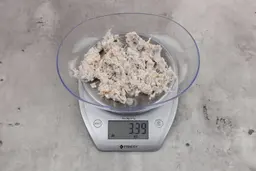 3.39 ounces of ground fish scraps from garbage disposal, displayed on digital scale, placed on a granite-looking table. Mess of assorted shredded bones and fibrous tissue.