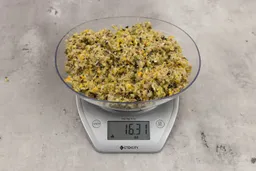 16.31 ounces of ground products from a garbage disposal, displayed on digital scale, placed on a granite-looking table. Mess of assorted scraps, including fibers, bones, etc.