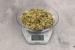 6.67 ounces of ground products from a garbage disposal, displayed on digital scale, placed on a granite-looking table. Visible fish pin bones in mess of assorted scraps.