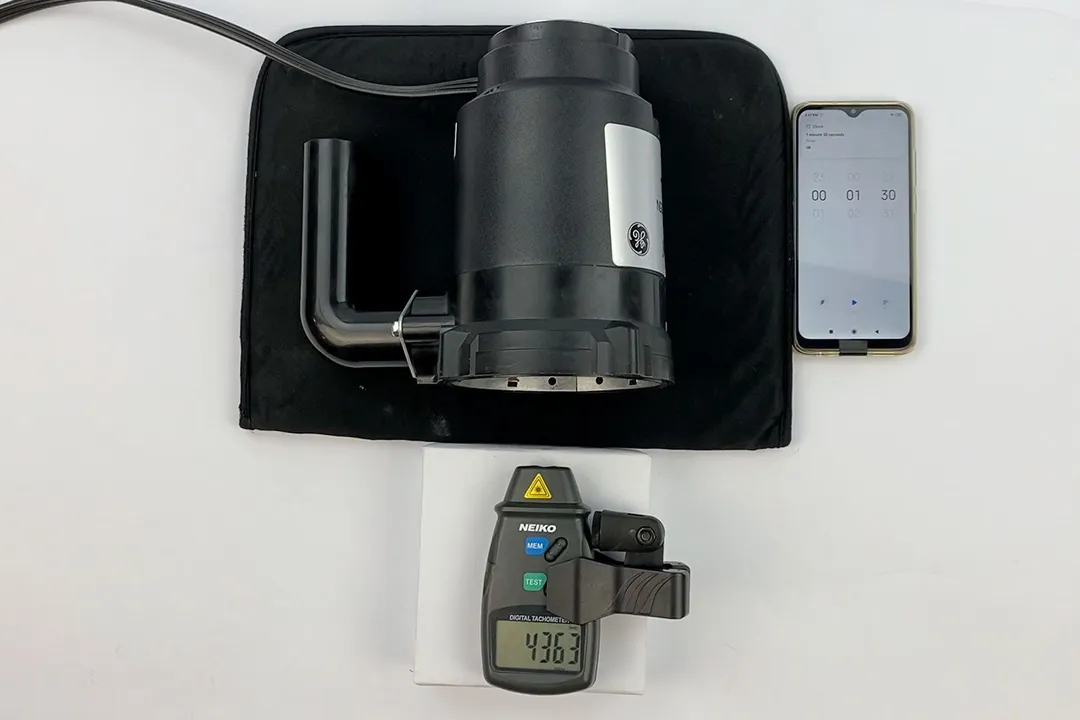 A digital tachometer is measuring the speed of the motor/flywheel of the GE GFC525N 1/2-HP garbage disposal in our speed test. A smartphone is running the timer app.