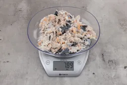 7.89 ounces of visible pin bones in a mass of raw meat and skin from fish scraps on digital scale on granite-looking top.