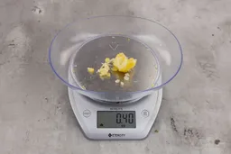 0.4 ounces of shredded pieces and one large piece of lemon peel from garbage disposal on digital scale on granite-looking table