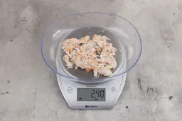 2.4 ounces of visible pin bones in a mass of raw meat and skin from fish scraps on digital scale on granite-looking top.