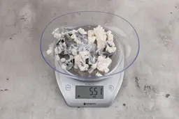 5.51 ounces of broken fish vertebrae and shredded fish skin on digital scale on granite-looking top.