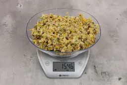 15.46 ounces of fish pin bones in mess of assorted scraps from garbage disposal on digital scale on granite-looking top.