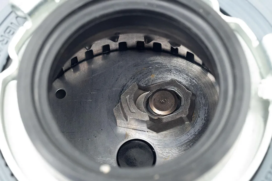 Top view through collar of InSinkErator Compact 3/4-hp garbage disposal into chamber after testing. Looking at layout of grinding components, showing swivel impellers, flywheel, and grater/grinder ring.