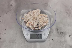 3.53 ounces of ground fish scraps from garbage disposal, displayed on digital scale, placed on granite-looking table. Mess of assorted shredded bones and raw fibrous tissue.