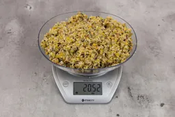 20.52 ounces of ground products from garbage disposal, displayed on digital scale, placed on granite-looking table. Mess of assorted scraps, including fibers, bones, etc.