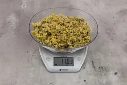11.03 ounces of fish pin bones in mess of assorted scraps from garbage disposal on digital scale on granite-looking top