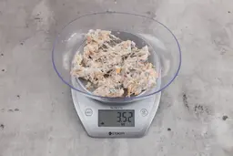 3.52 ounces of ground fish scraps from garbage disposal, displayed on digital scale, placed on granite-looking table. Mess of assorted shredded fish bones and raw fibrous tissue. 