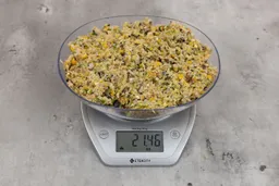 21.46 ounces of ground products from garbage disposal, displayed on digital scale, placed on granite-looking table. Mess of assorted scraps, including fibers, bones, etc.