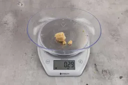 0.29 ounces of ground products from a garbage disposal, displayed on a digital scale, placed on a granite-looking table. Broken up pieces of corncob.
