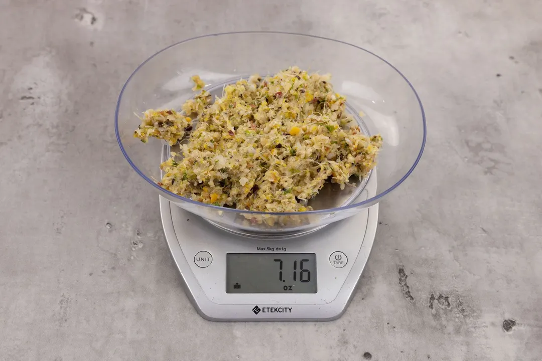 7.16 ounces of ground products from garbage disposal, displayed on digital scale, placed on granite-looking table. Mess of assorted scraps, including dietary fibers, shredded bones, etc.