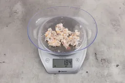1.84 ounces of ground fish scraps from garbage disposal, displayed on digital scale, placed on granite-looking table. Mess of assorted shredded bones and raw fibrous tissue. 