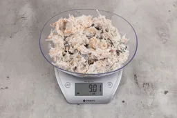 0.92 ounces of ground chicken scraps from garbage disposal, displayed on digital scale, placed on granite-looking table. Mess of shredded soft tissues and shredded bones.
