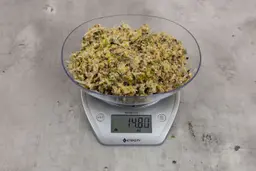 14.8 ounces of assorted scraps from garbage disposal on digital scale on granite-looking top. 