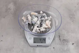 4.41 ounces of fish vertebrae in a mass of shredded fish skin, on digital scale, on granite-looking top.