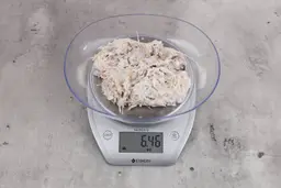 6.46 ounces of visible pin bones in a mass  of raw fibrous tissue from fish scraps, on digital scale, on granite-looking top.