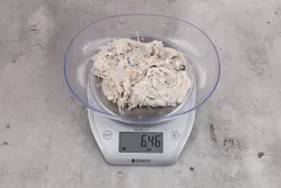 6.46 ounces of visible pin bones in a mass  of raw fibrous tissue from fish scraps, on digital scale, on granite-looking top.