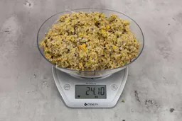 24.1 ounces of ground assorted scraps, including dietary fibers, bones, etc., on digital scale, on granite-looking top.