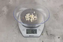 0.23 ounces of shredded pieces of fish backbone, dietary fibers, and fish meat, on digital scale, on granite-looking top.