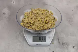 8.11 ounces of visible fish pin bones in mass of ground assorted scraps, on digital scale, on granite-looking top.
