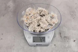 7.2 ounces of visible pin bones among mess of raw fibrous tissue from fish scraps, on digital scale, on granite-looking top.