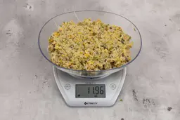 11.96 ounces of ground assorted scraps, including dietary fibers, bones, etc., on digital scale, on granite-looking top.