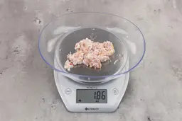 1.86 ounces of ground chicken scraps from garbage disposal, displayed on digital scale, placed on granite-looking table. Mess of shredded tissues and shredded bones.