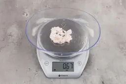 0.67 ounces of ground chicken scraps from garbage disposal, displayed on digital scale, placed on granite-looking table. Mess of shredded soft tissues and shredded bones.