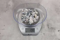 2.8 ounces of fish vertebrae among mess of shredded fish skin, on digital scale, on granite-looking top.