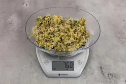 7.6 ounces of visible fish pin bones in mess of ground assorted scraps, on digital scale, on granite-looking top.