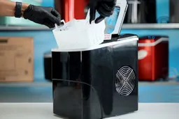 A basket of ice being lifted out of a portable countertop ice maker.