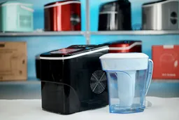 The AGLucky Ice Maker HZB-12/B on a countertop with a water pitcher filter to the right.