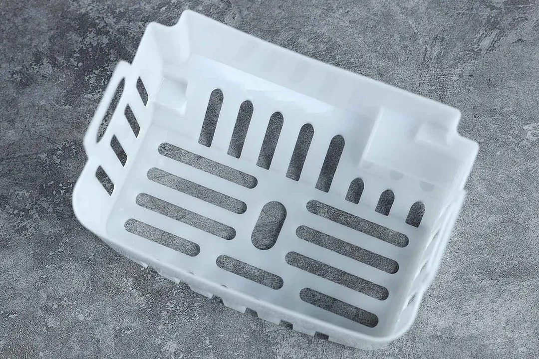 Top down and close up view of a plastic ice basket for a portable ice making machine.