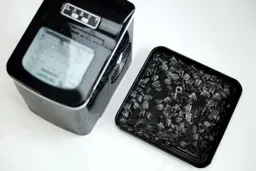 The AGLucky countertop ice maker with ice spread in a baking tray to the right showing the level of ice quality degradation over an 8-hour period.