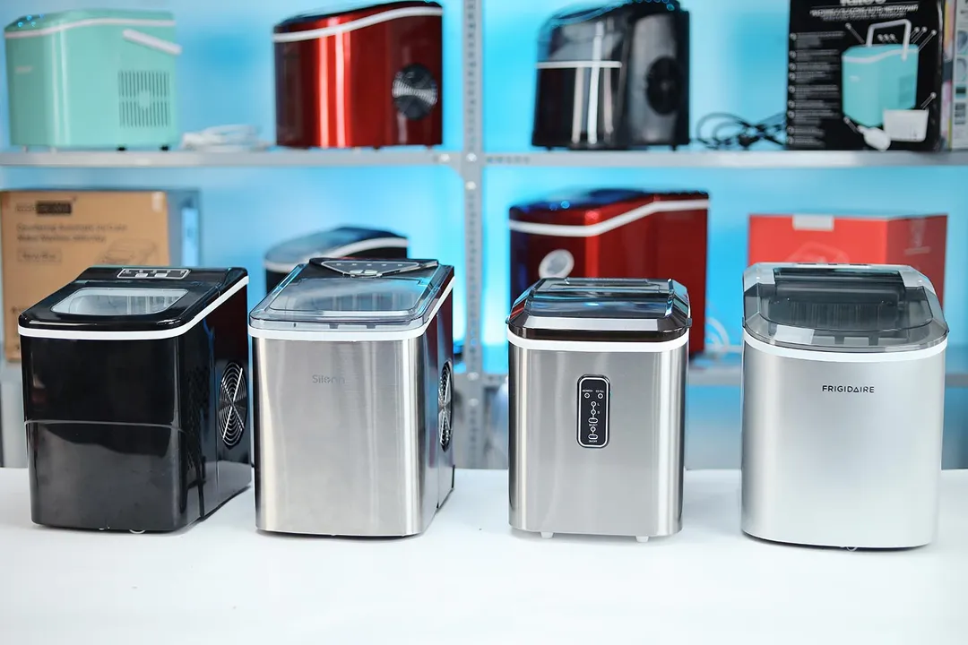 Four best countertop ice makers on a countertop with two rows of additional ice makers on a shelf in the background.
