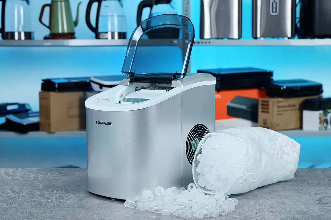 A countertop portable ice maker on a countertop with a 12 kg bag of ice to the right side.