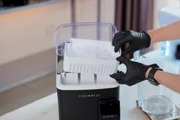 A full basket of ice being removed from a countertop portable ice maker.