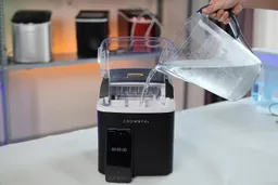 Chilled water being poured into a portable ice maker machine.