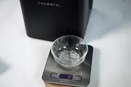 A portable ice maker with a bowl of freshly made ice on a scale showing 17 grams in total.