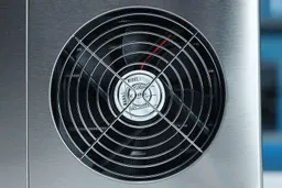 A close up of a stainless steel extraction fan on the right hand side of a portable countertop ice maker.