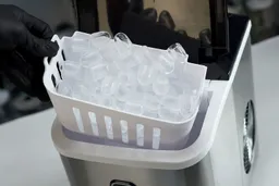 A full basket of ice being removed from a countertop buller ice maker.